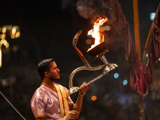Hindu priest holding a burning aarti during the Ganga aarti ceremony in Varanasi, India, showcases a vibrant display of devotion and spirituality in a major religious hub for Hinduism