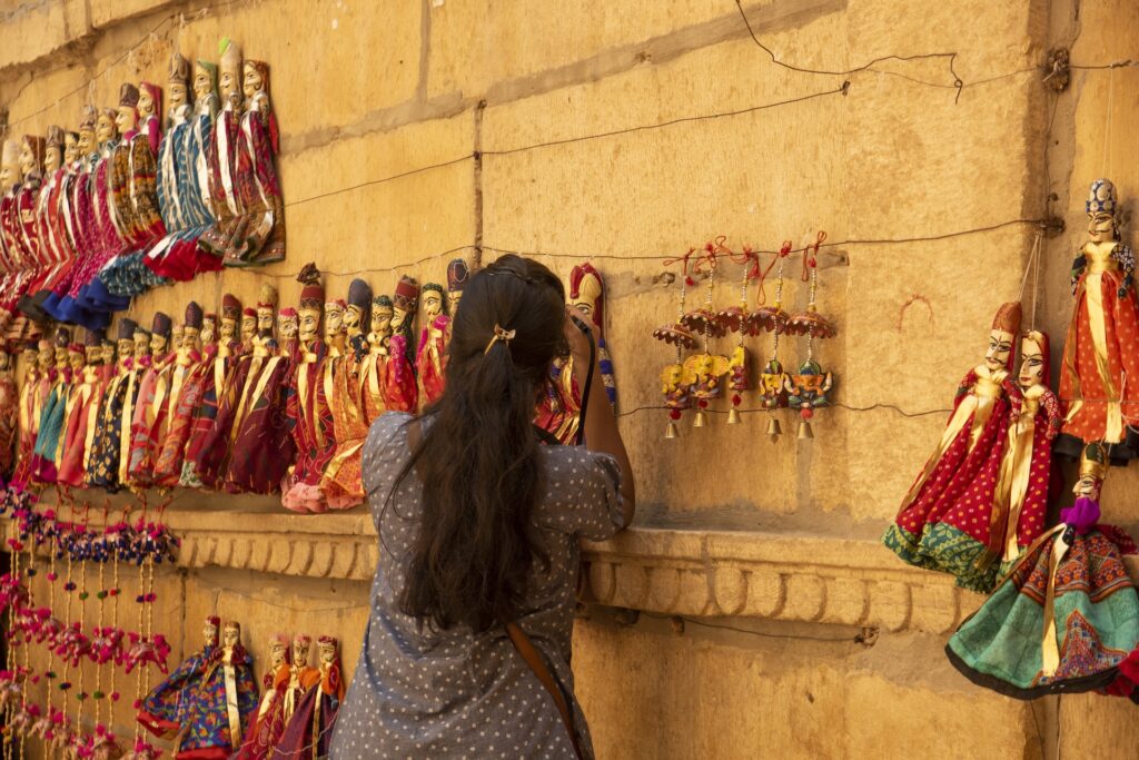 Woman tourist taking photos of puppets on the street of Jaisalmer, India.