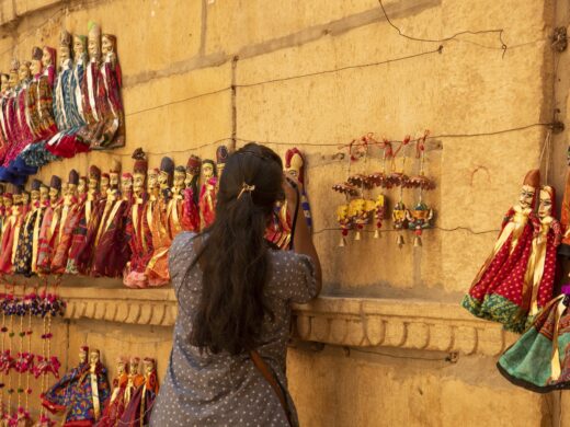 Woman tourist taking photos of puppets on the street of Jaisalmer, India.